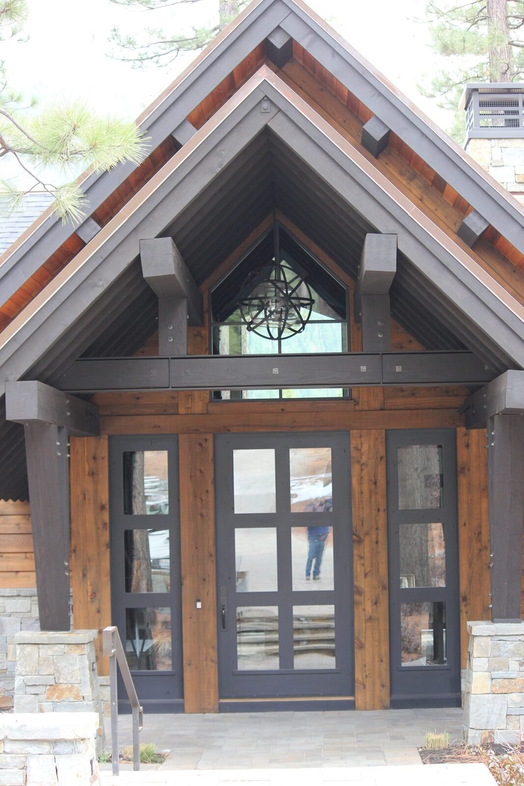 Custom home dark painted entry with copper accents globe chandelier and timber frame Martis Camp Truckee CA