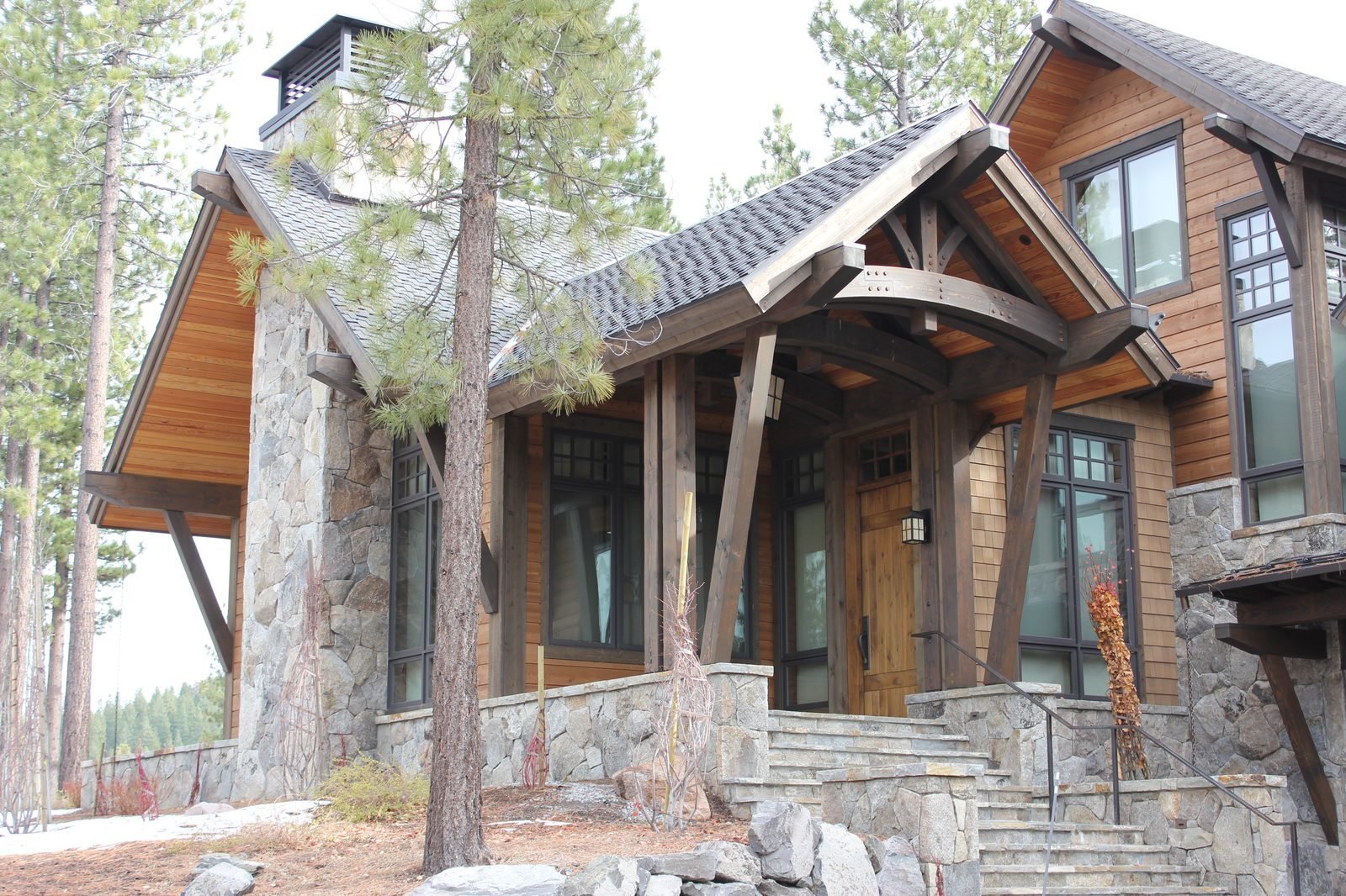 Custom mountain home exterior heavy timber frame stone base cedar siding Martis Camp Truckee CA