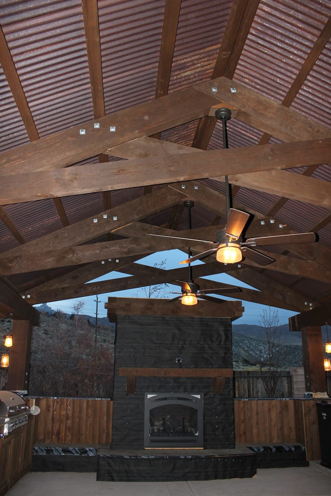 Covered outdoor kitchen with timber frame fireplace BBQ and pendant lighting Reno NV